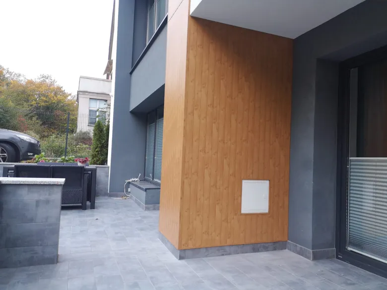 Narożnik budynku z panelem aluminiowym w dekorze drewna przy tarasie